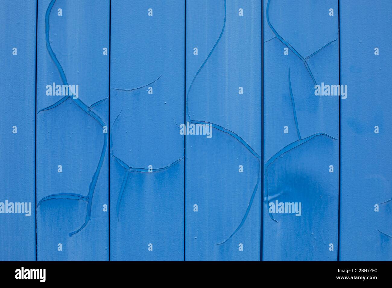Metal siding painted in blue with cracks and erosion, old wall