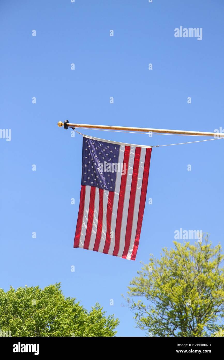 American flag against a blue sky over trees in springtime Stock Photo