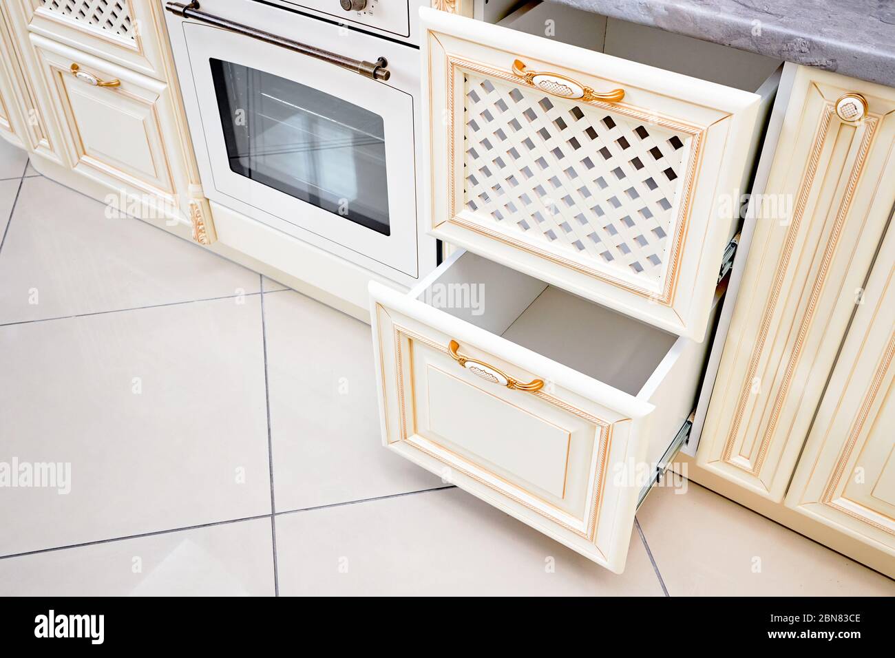https://c8.alamy.com/comp/2BN83CE/interior-of-modern-kitchen-in-classic-style-with-golden-elements-in-beige-colors-with-built-in-appliances-drawers-for-plates-or-dishes-shelf-under-co-2BN83CE.jpg