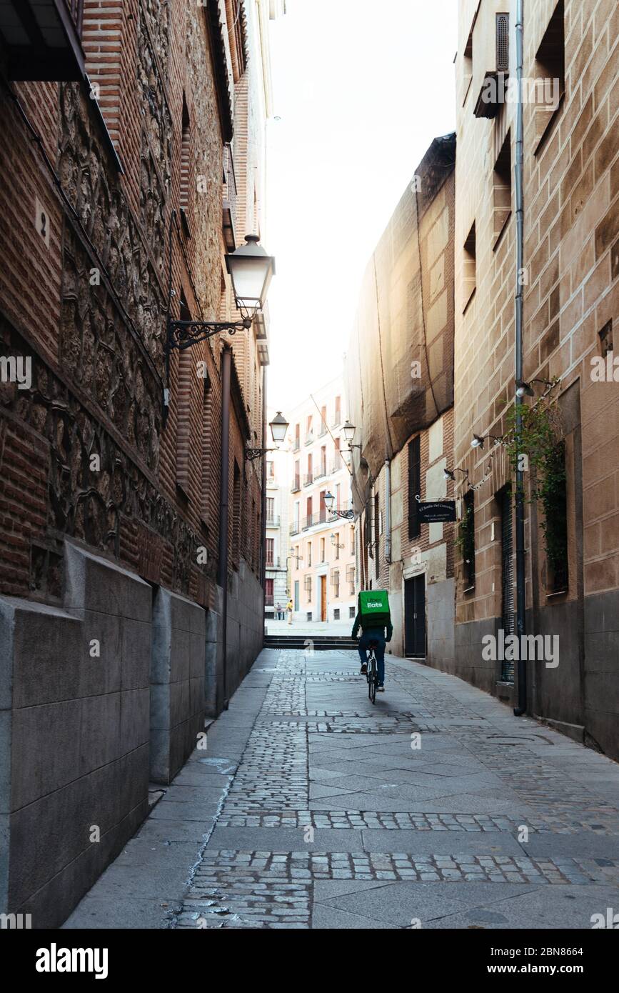 Madrid, Spain - November 1, 2019: Uber Eats rider cycling through an alley in old Madrid. Stock Photo