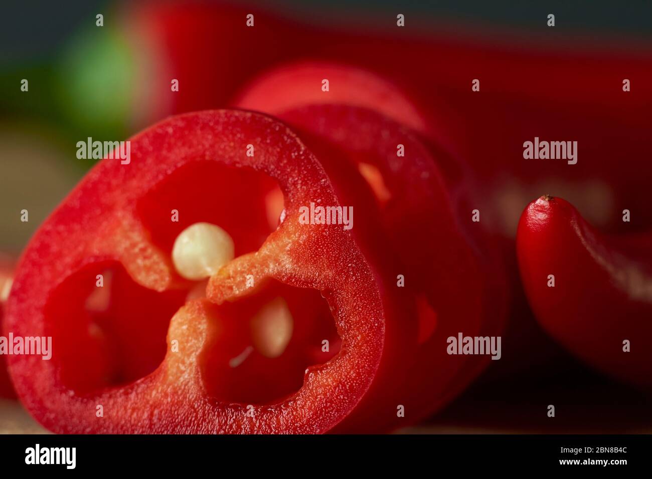 Close-up of sliced red hot chili peppers on wooden cutting board, selective focus Stock Photo