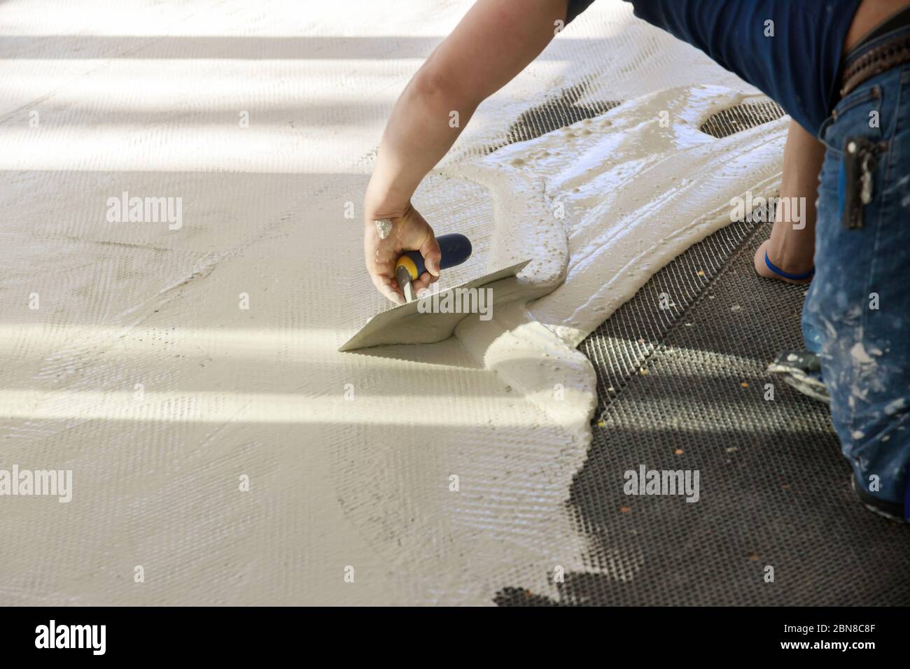 Professional worker troweling mortar concrete in preparation for laying for tiler on the floor