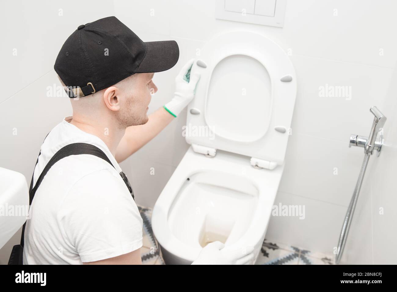Plumber installing toilet bowl in restroom, work in bathroom Stock Photo
