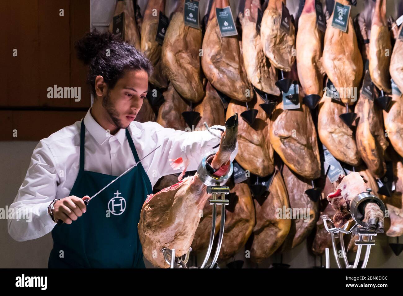 Male shop worker skilfully slices Iberian ham at Viandas, Leadenhall Market, London, UK Stock Photo