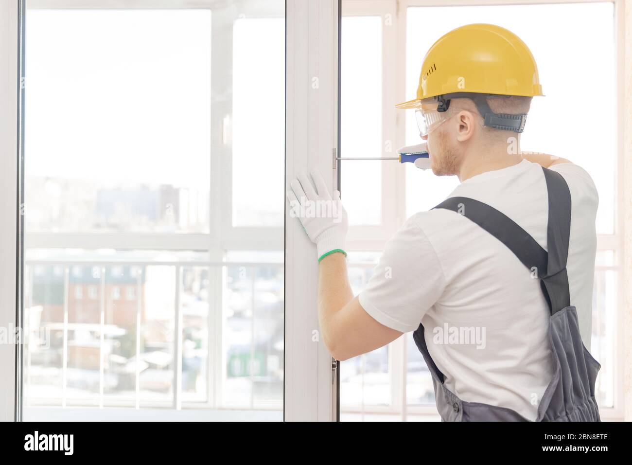 Worker man installs plastic windows white lock and seal adjustment