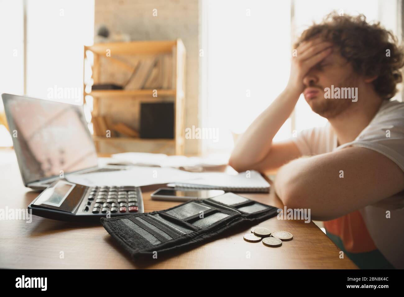 Caucasian upset and despair man watching financial and economical graphs going down during coronavirus quarantine, problems. Worldwide crisis for business and people. Income reduction, lack of money. Stock Photo
