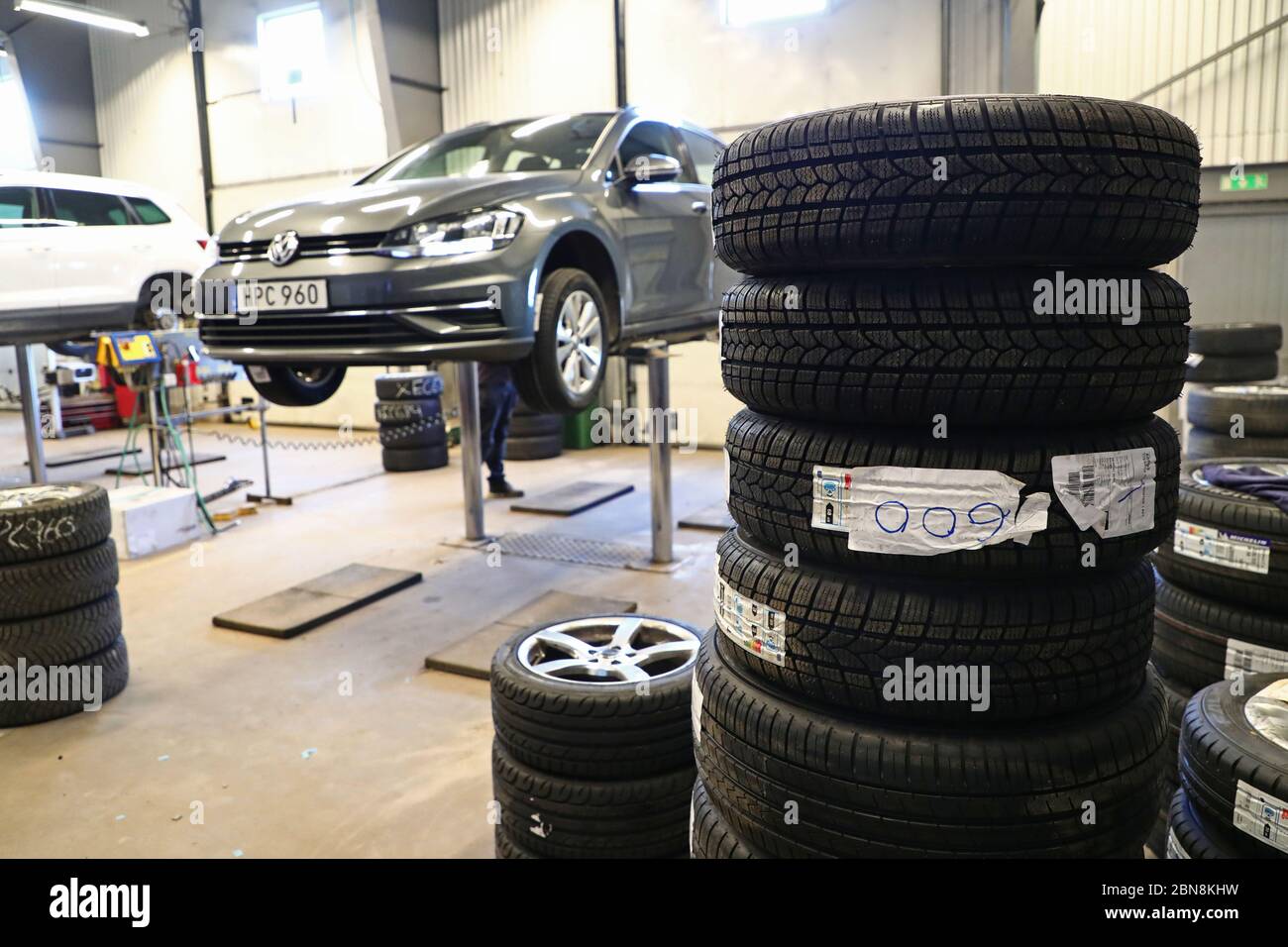 Car mechanic changing winter tires and mounting summer tires on wheels