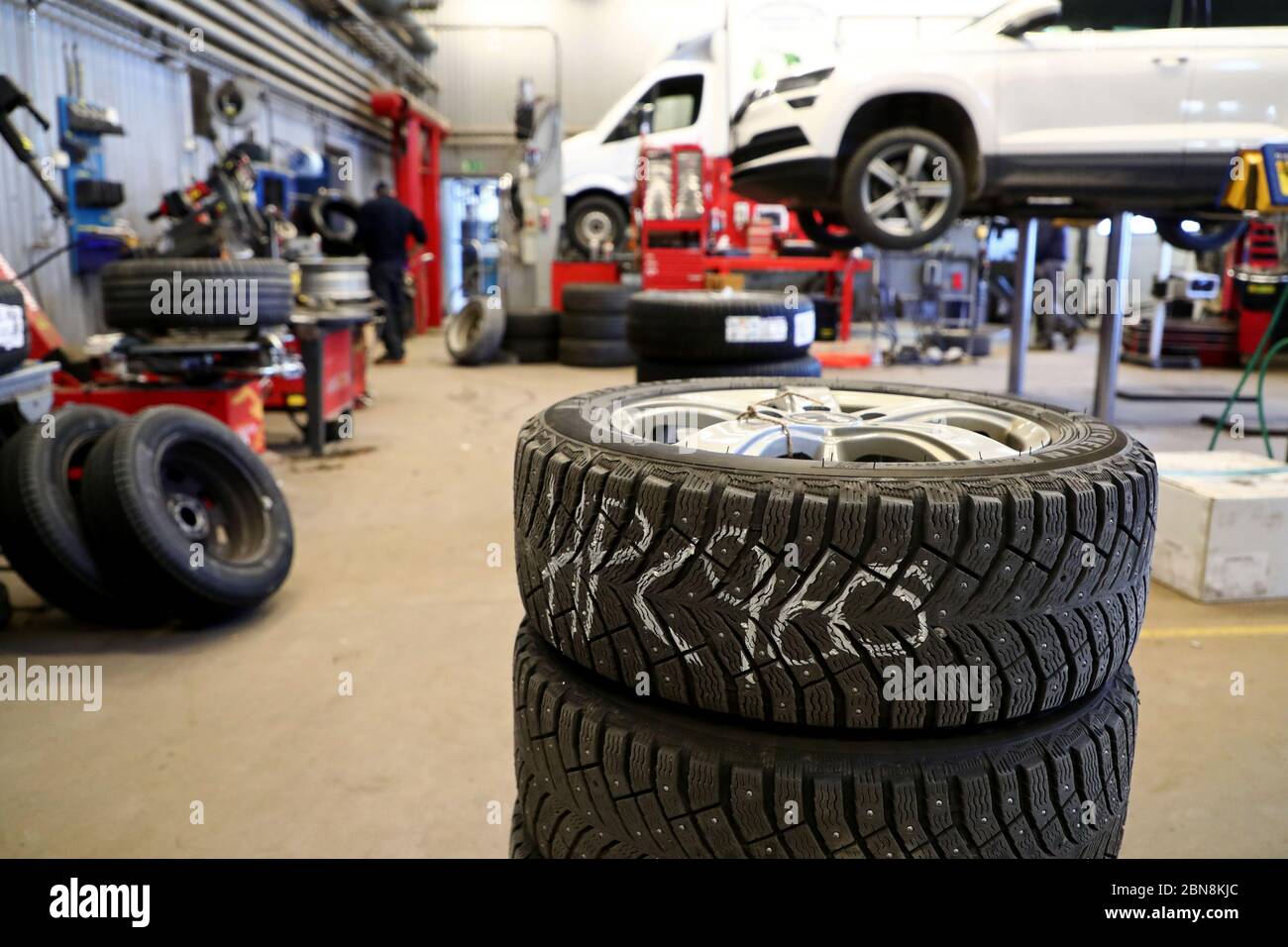 Car mechanic changing winter tires and mounting summer tires on wheels