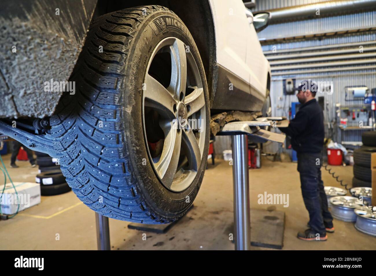 Car mechanic changing winter tires and mounting summer tires on wheels