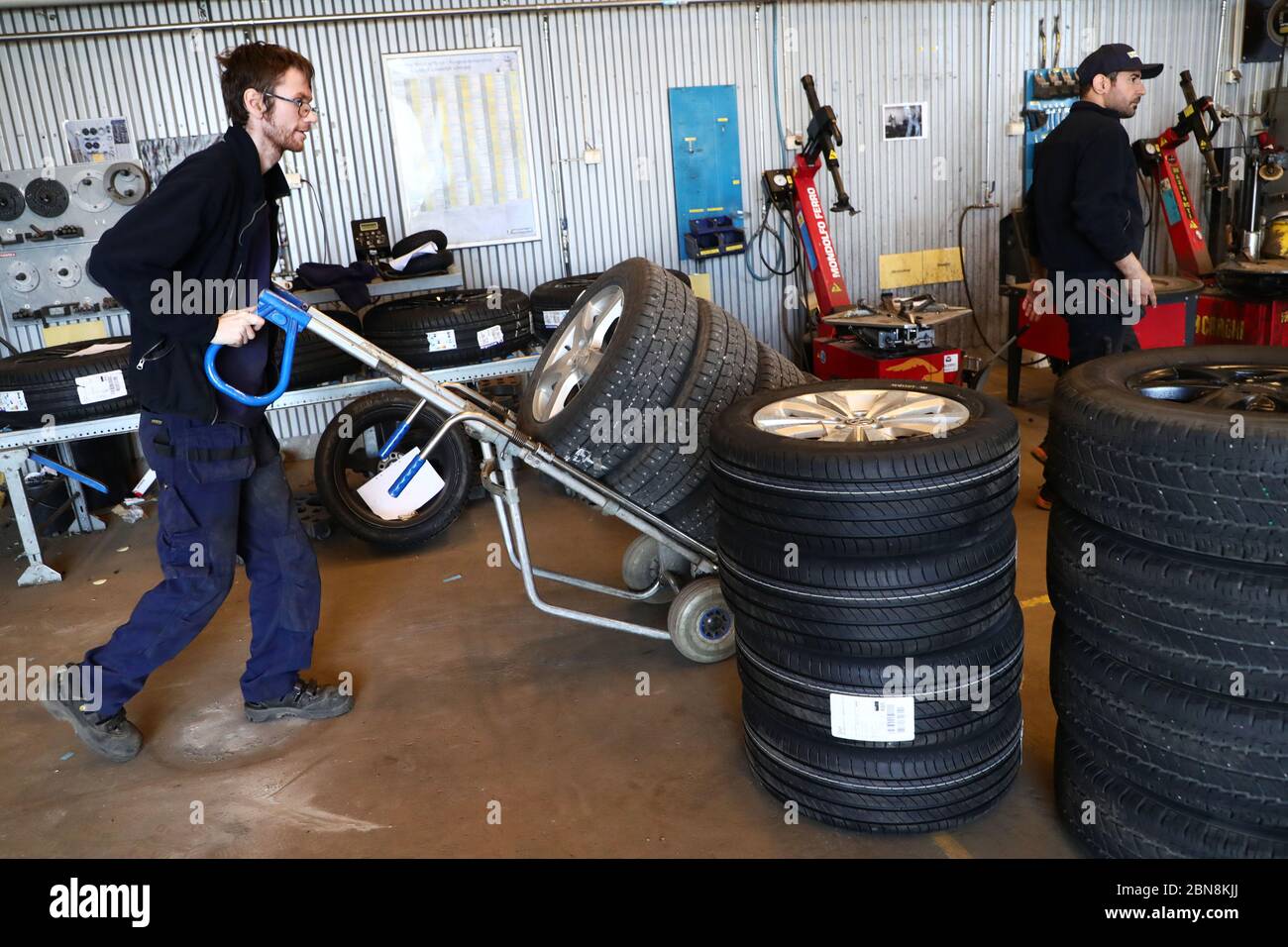 Car mechanic changing winter tires and mounting summer tires on wheels