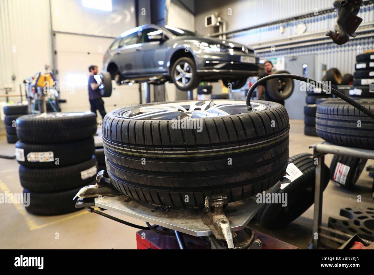 Car mechanic changing winter tires and mounting summer tires on wheels