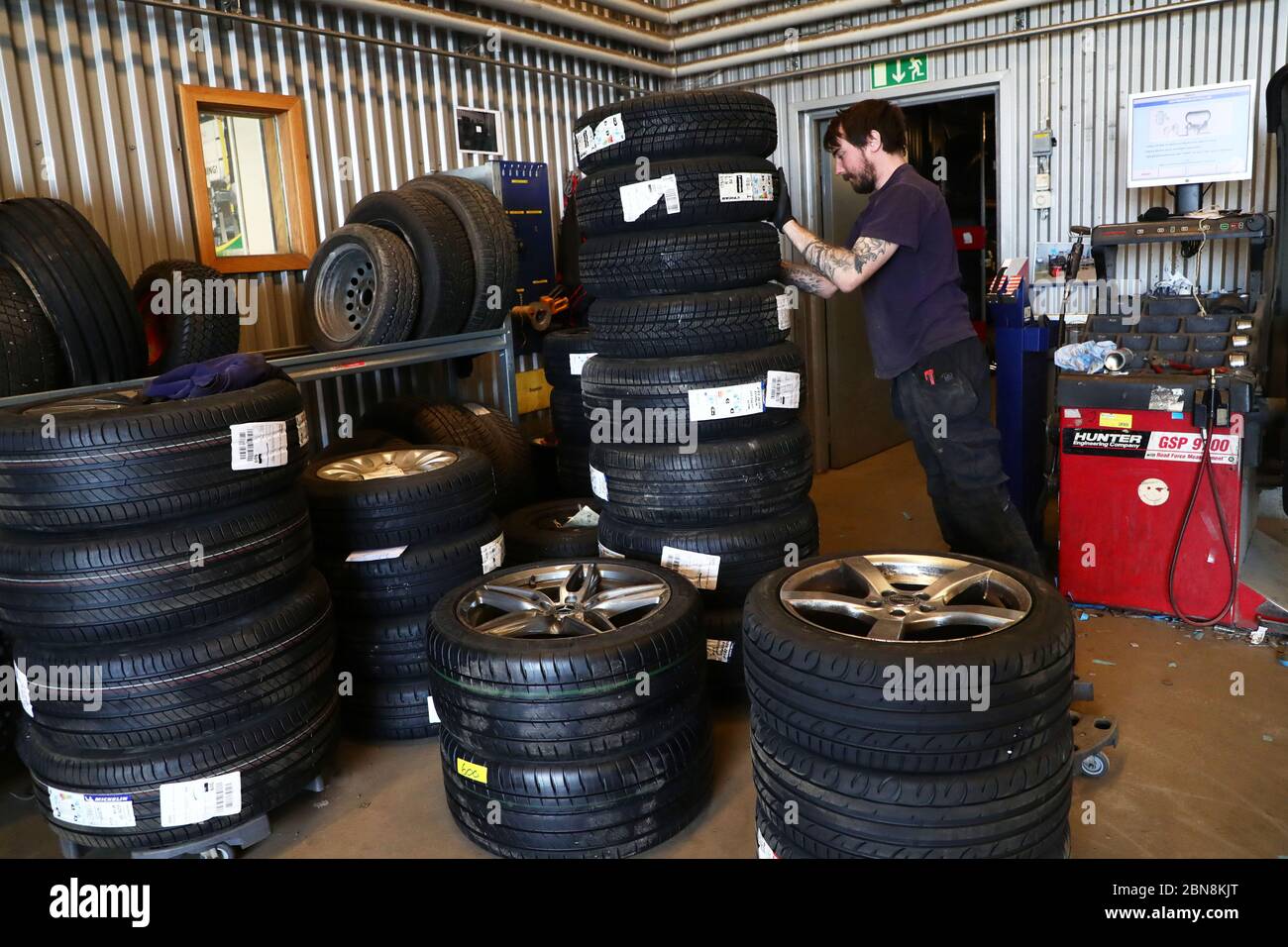 Car mechanic changing winter tires and mounting summer tires on wheels