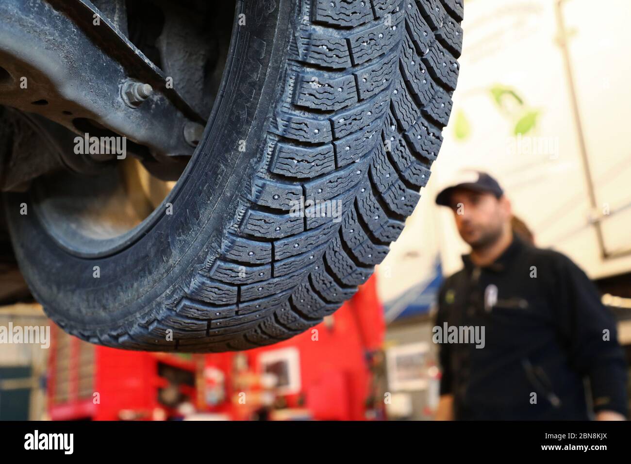 Car mechanic changing winter tires and mounting summer tires on wheels