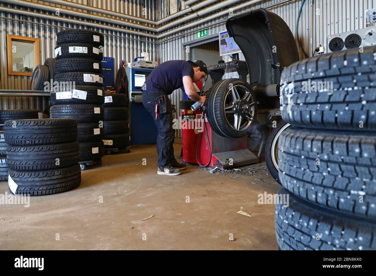 Car mechanic changing winter tires and mounting summer tires on wheels