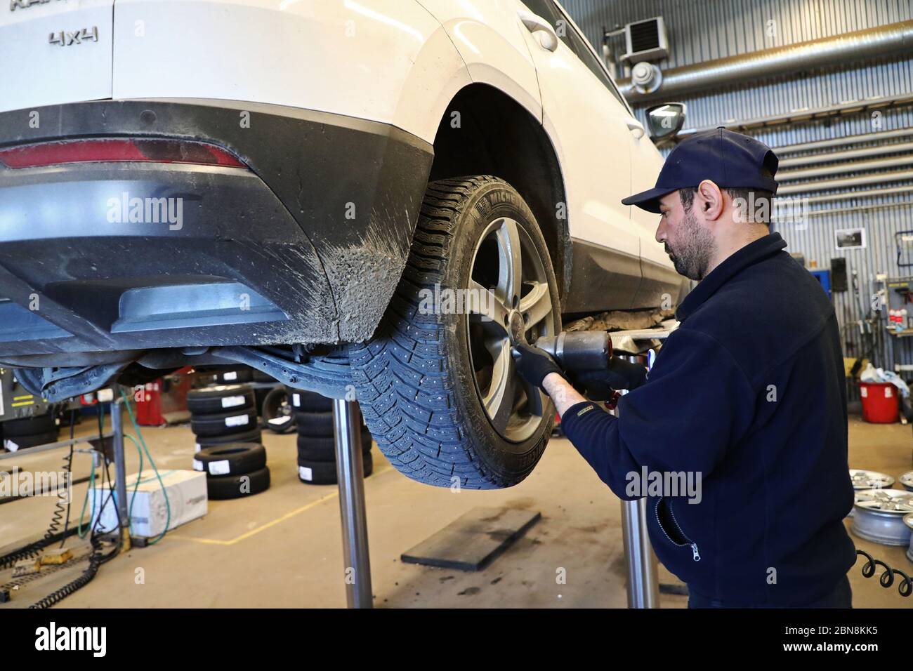 Car mechanic changing winter tires and mounting summer tires on wheels