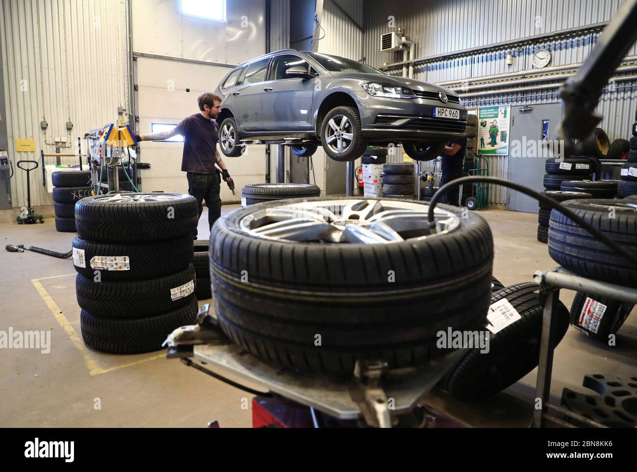Car mechanic changing winter tires and mounting summer tires on wheels