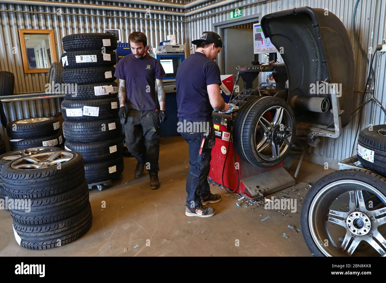 Car mechanic changing winter tires and mounting summer tires on wheels