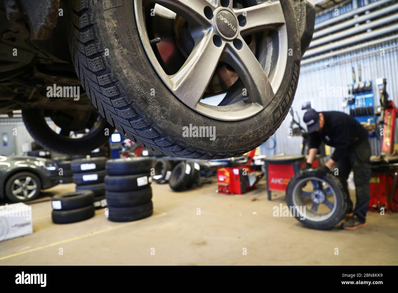 Car mechanic changing winter tires and mounting summer tires on wheels