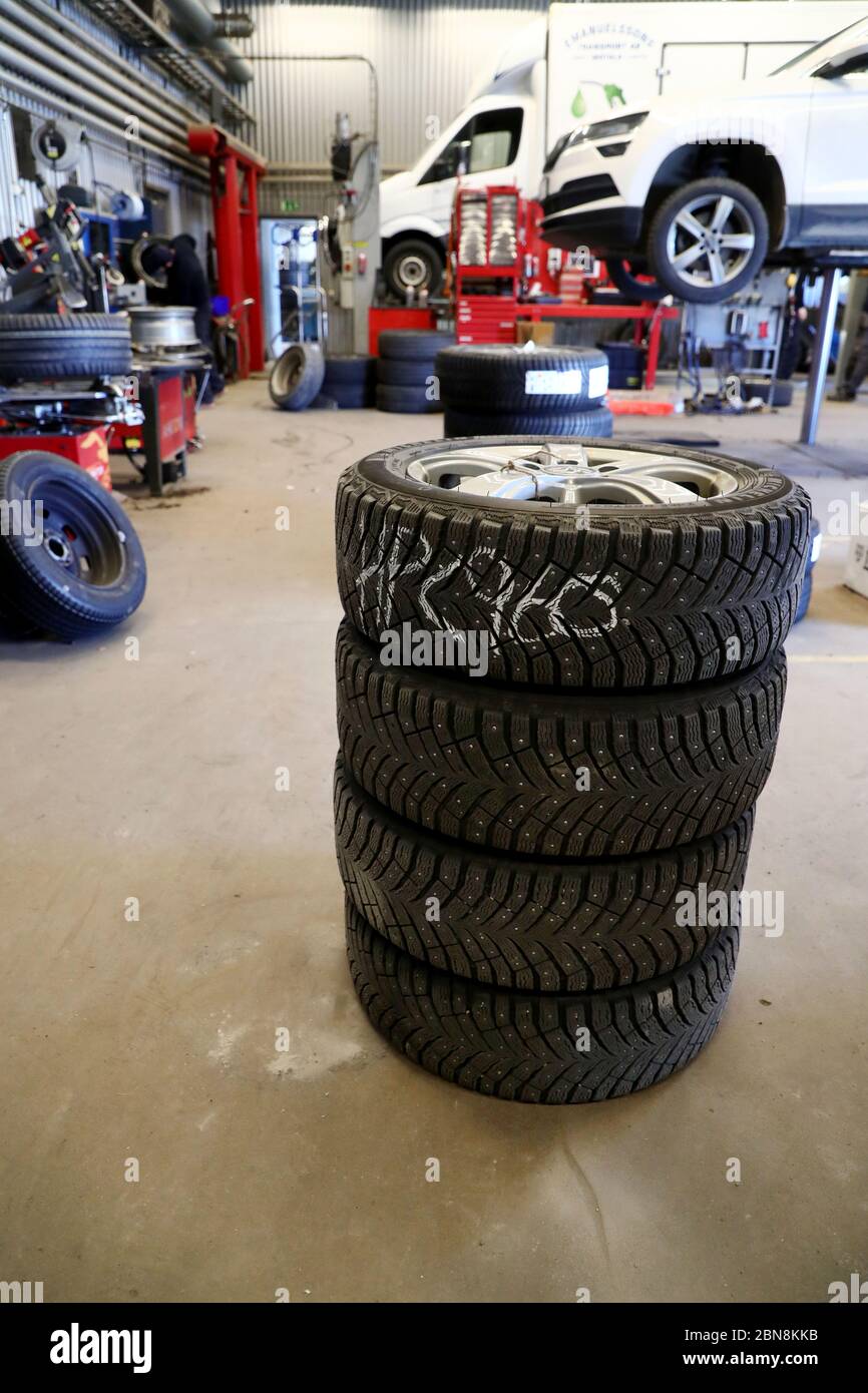 Car mechanic changing winter tires and mounting summer tires on wheels