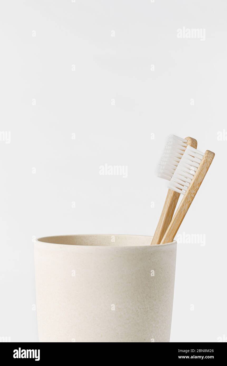 Bamboo toothbrushes in eco cup on white background. Copy space, close ...