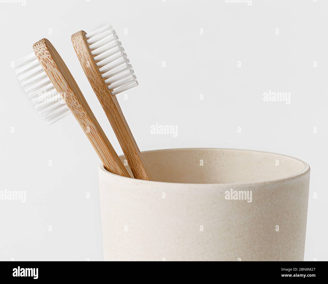 Bamboo toothbrushes in eco cup on white background. Copy space, close ...