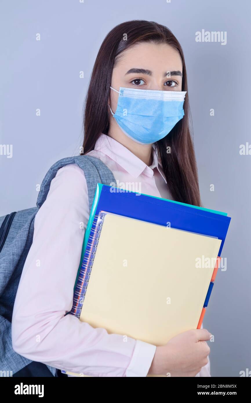 High school girl with mask on her face going back to school. Student girl ready for school during the coronavirus pandemic. Focus on her face. Stock Photo