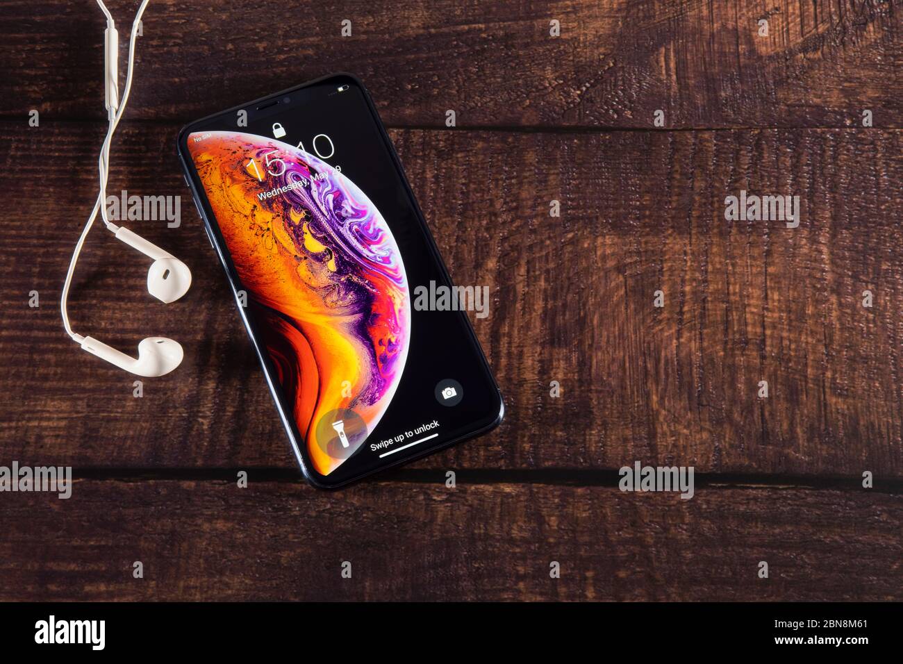 Galati, Romania - May 29, 2019: Apple launch the new smartphone iPhone XS and iPhone XS Max. iPhone Xs Max with headphones on wooden table. Stock Photo