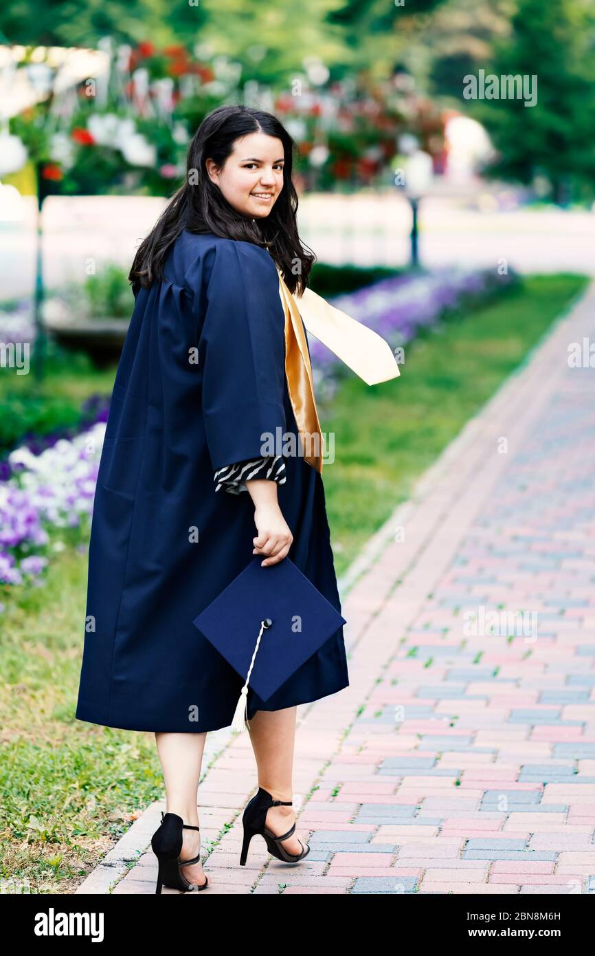 Smiling student woman on graduation day looking at camera. Stepping confidently into the future concept. Focus on her face. Stock Photo