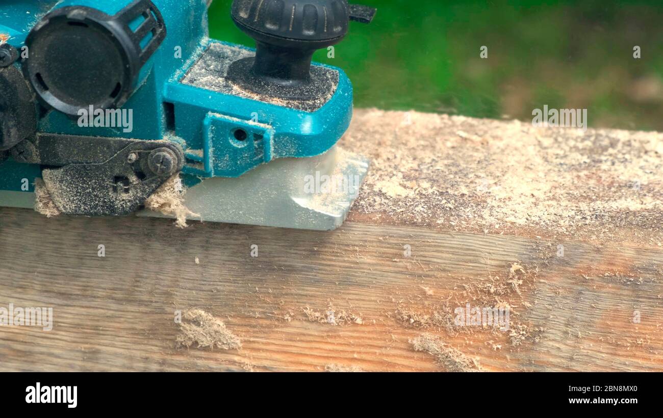 Worker planing electric planer piece of wood. Stock Photo