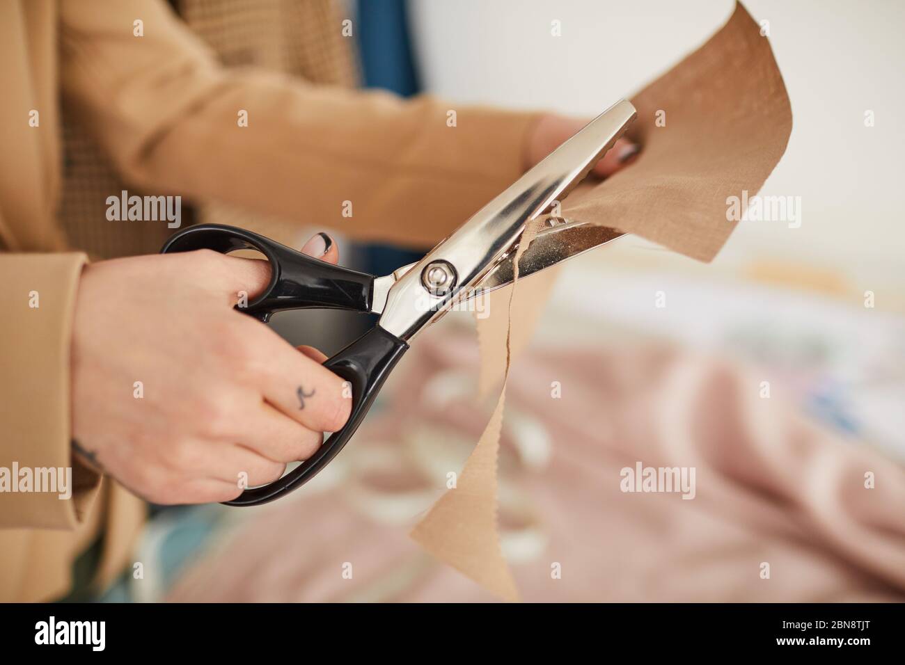 Closeup of woman hands holding scissors and cutting plaid fabric for sewing  clothes - a Royalty Free Stock Photo from Photocase