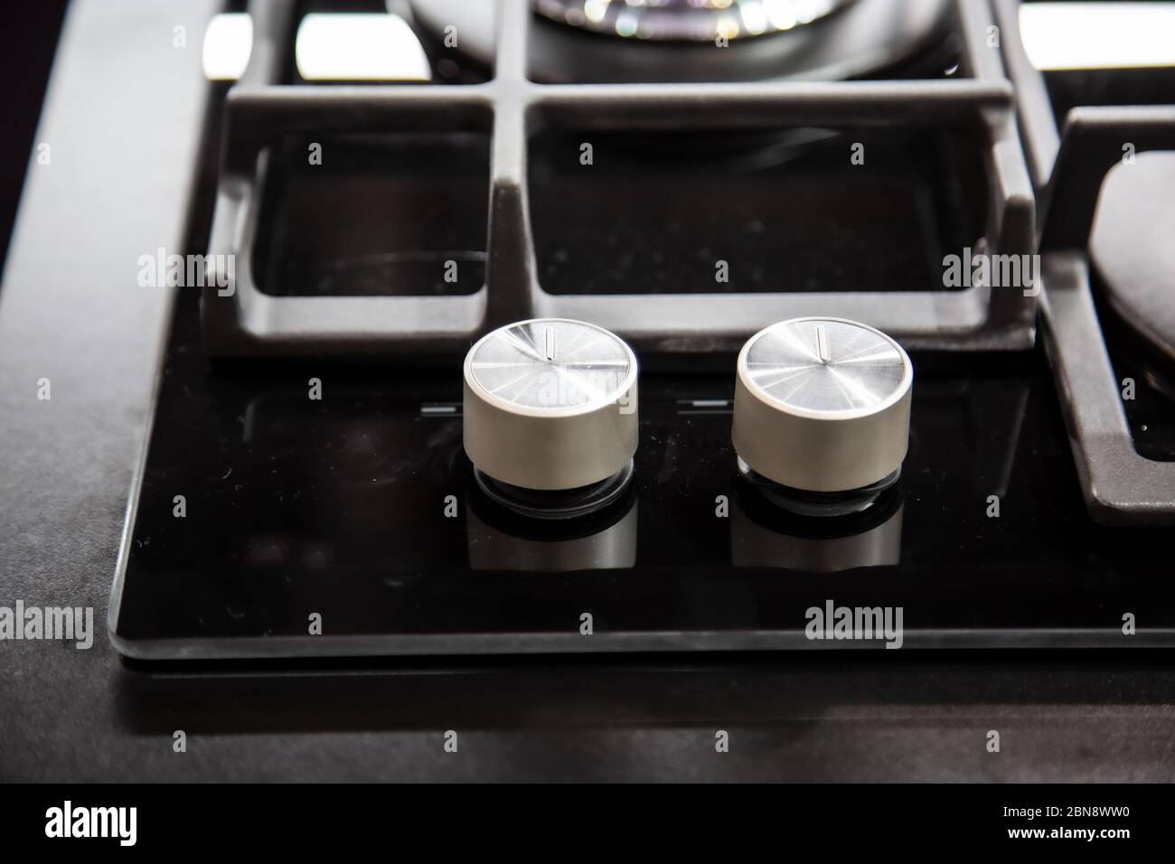 gas stove burner knobs with black mirror surface of cooker and stainless steel grills. top view