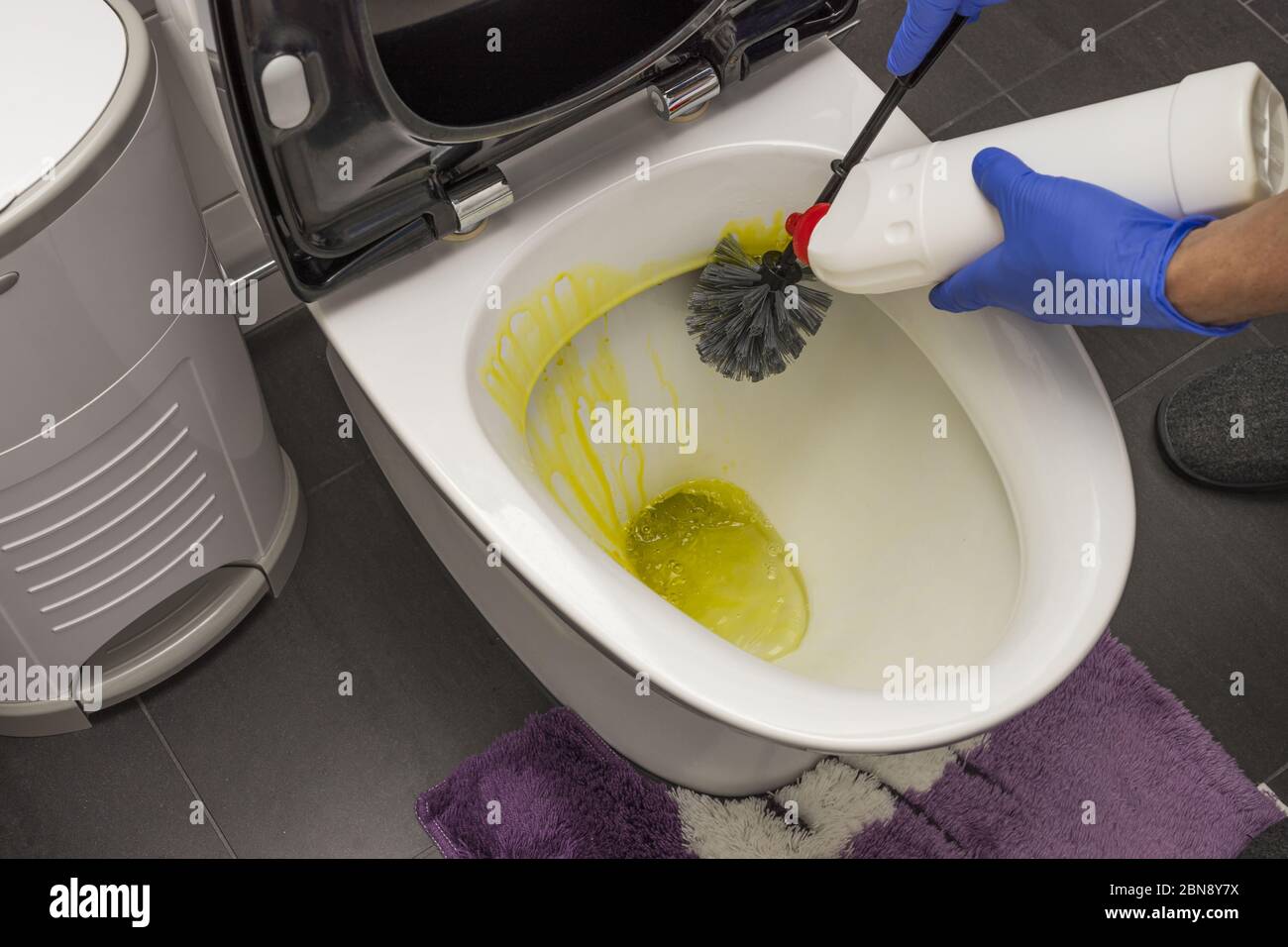 Close up view of male hands in blue gloves cleaning toilet seat. Hygiene concept. Stock Photo
