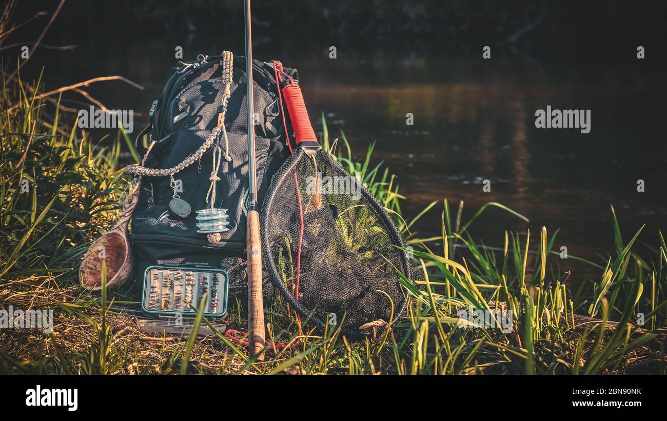 Fishing rod, backpack and fishing gear on the river bank. Tenkara. Stock Photo