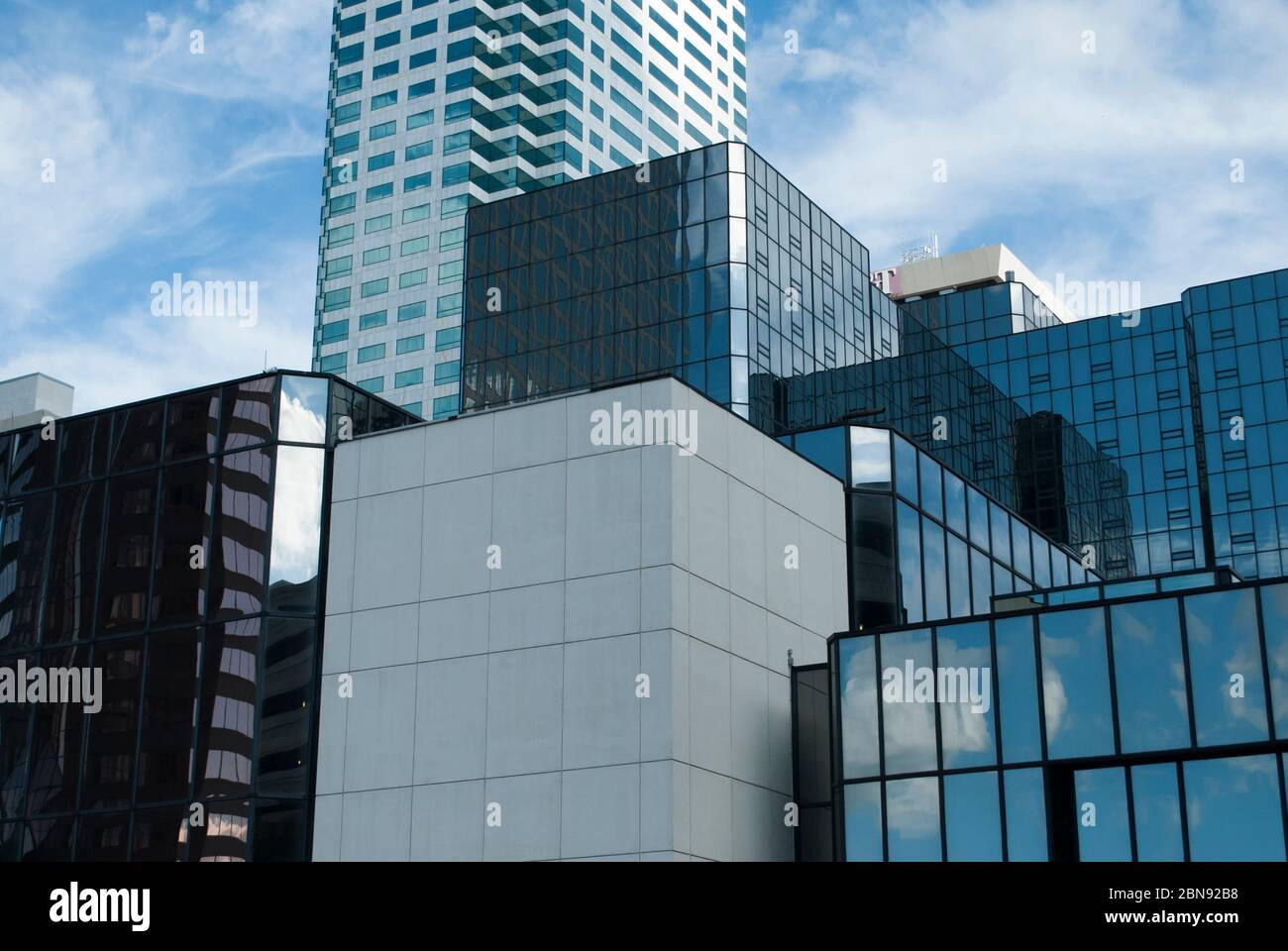 Cubic shape of the modern business buildings made from glass with reflections of blue sky with white clouds. Stock Photo