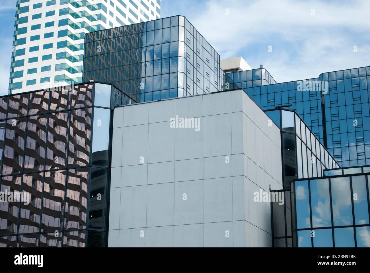 Cubic shape of the modern business buildings made from glass with reflections of blue sky with white clouds. Stock Photo