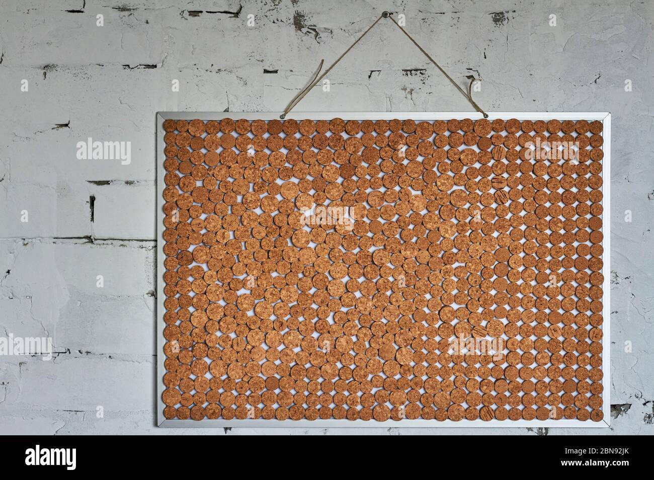 Homemade chopped wine cork note board on brick wall, selective focus Stock Photo
