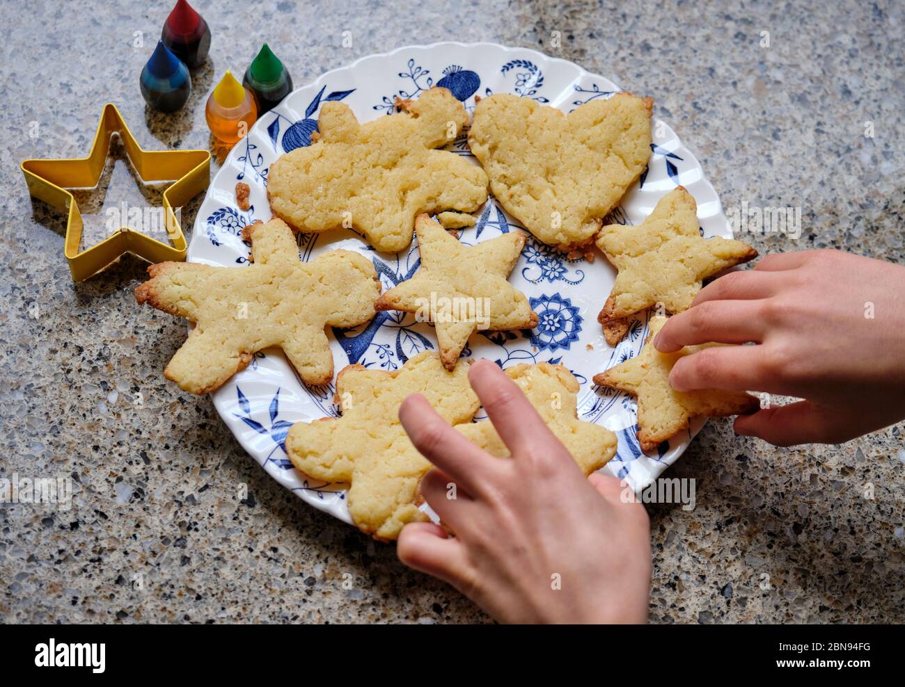 Hands of young boy organising the butter cookies he baked as project during  lock-down Stock Photo