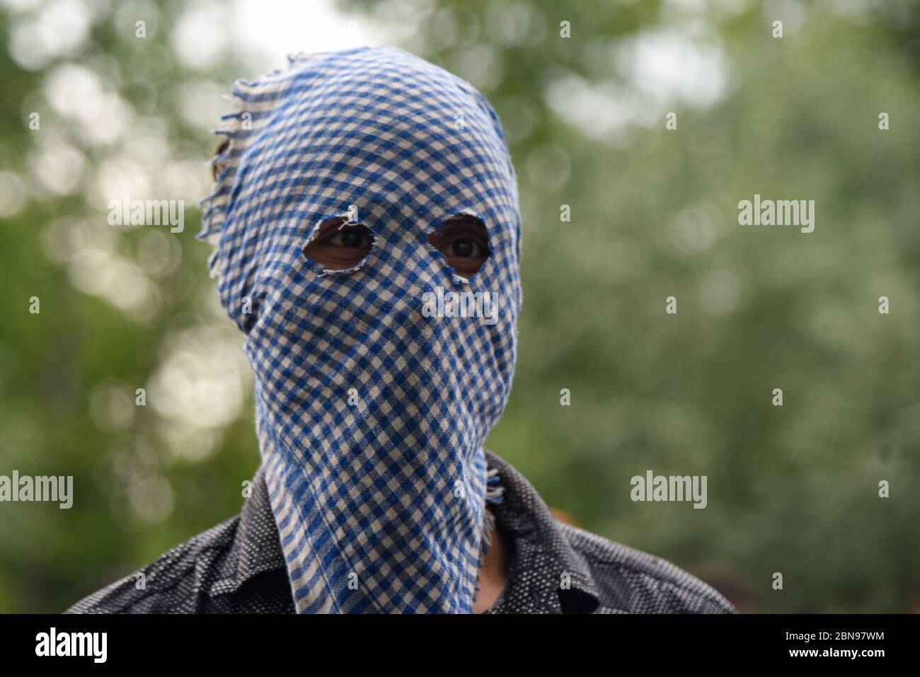 A masked Kashmiri man looks on while mourning during the funeral.A civilian identified as Peer Mehrajudin, was shot dead by paramilitary CRPF men (central reserve police force) at Kawoosa, Narbal in Central Kashmir’s Budgam district when he allegedly refused to stop at two check points, local media reports. Stock Photo