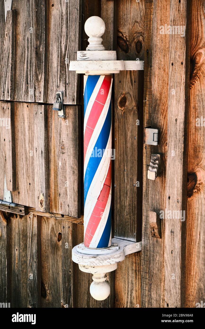 American barber pole on the exterior wall of a small town barber shop in rural Alabama, USA. Stock Photo