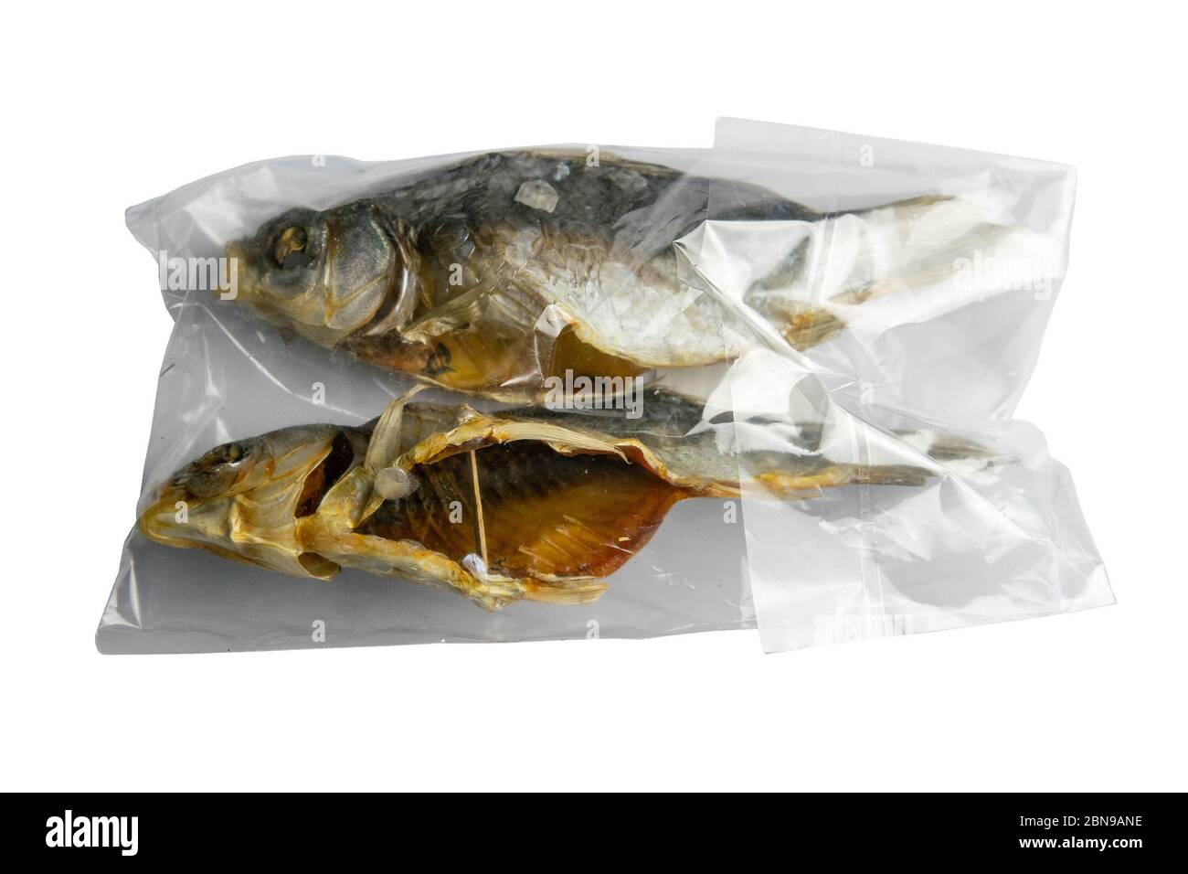Dried salted crucian fishes in a transparent package isolated on white background. Snack to beer Stock Photo