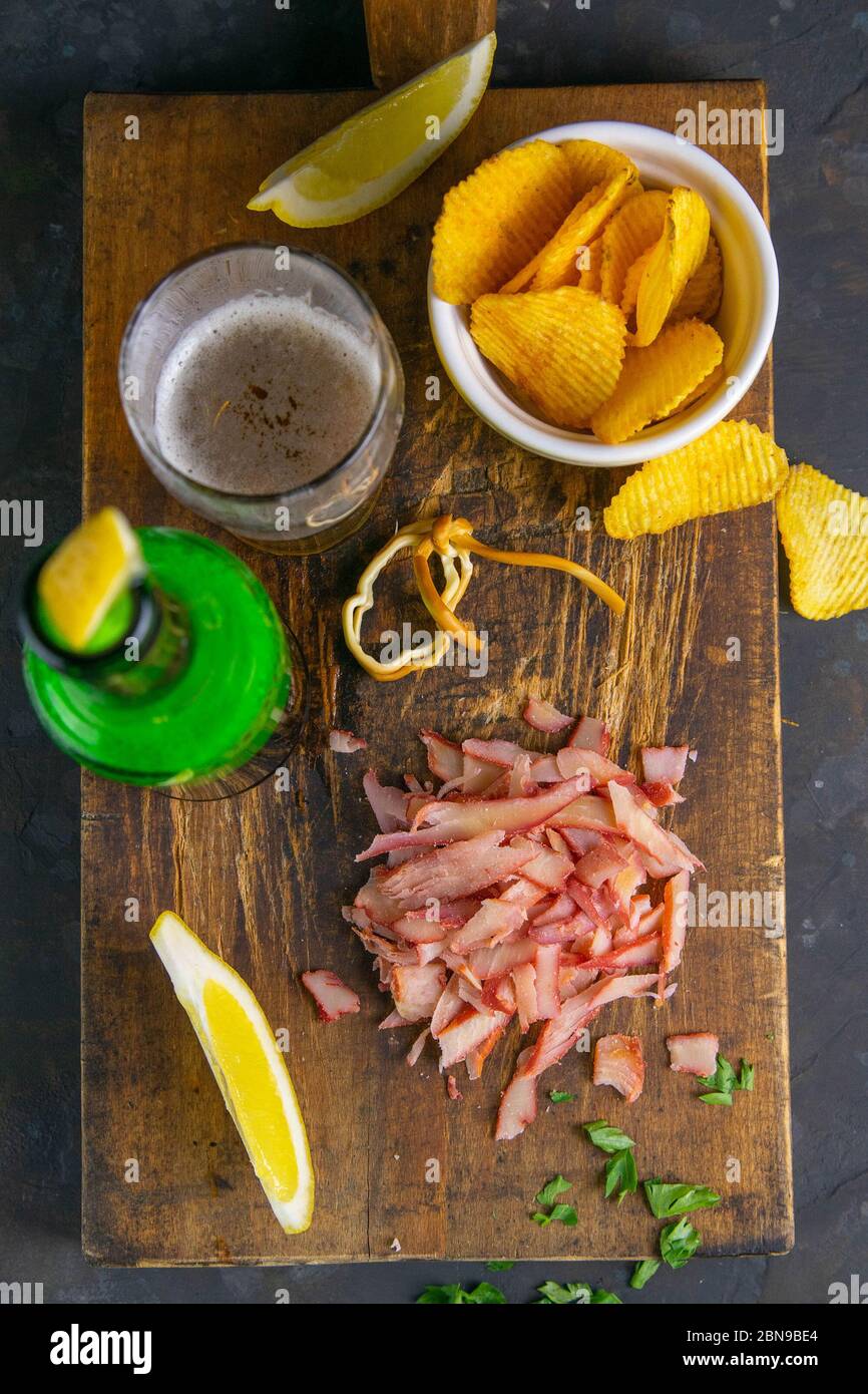 Crab rings with beer, lemon and potato chips on dark wooden board ...