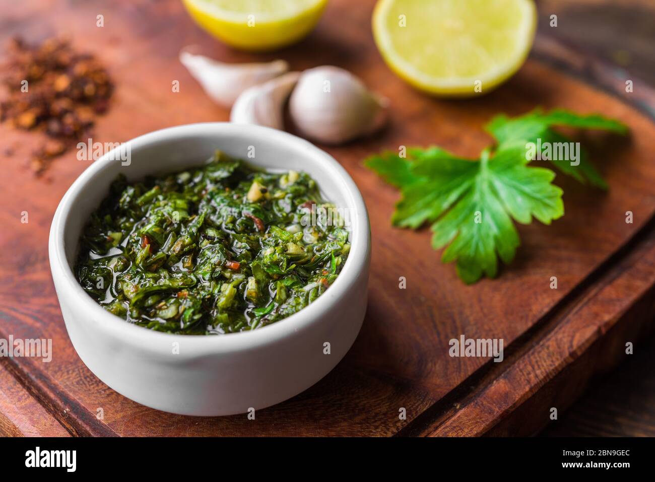 Traditional Argentinian chimichurri sauce against wooden background. Stock Photo