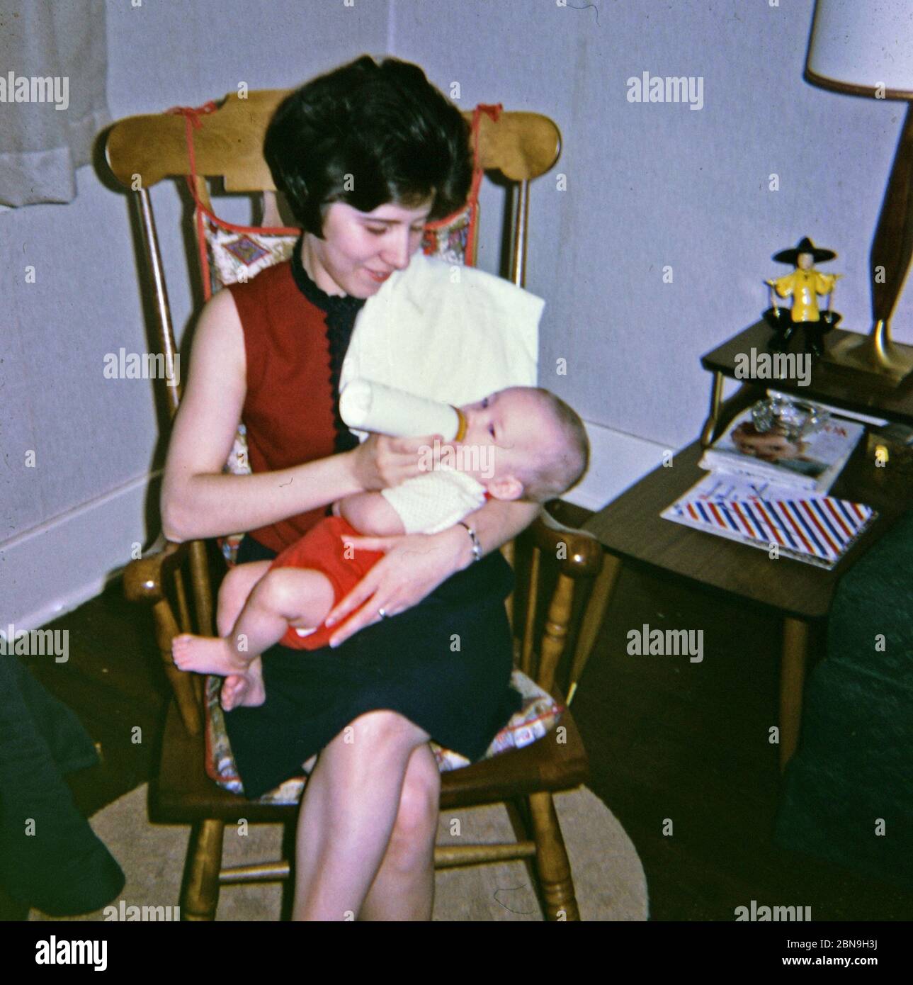 A mother feeding her five month old baby a bottle while sitting in a