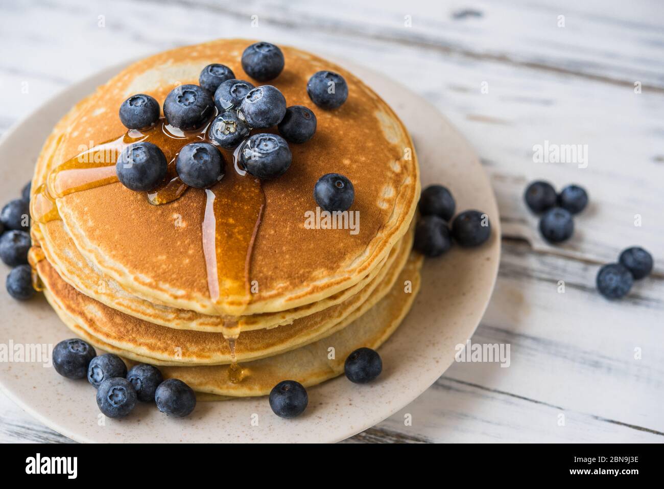 Close up of fluffy pancakes with maple syrup and blueberries. Stock Photo
