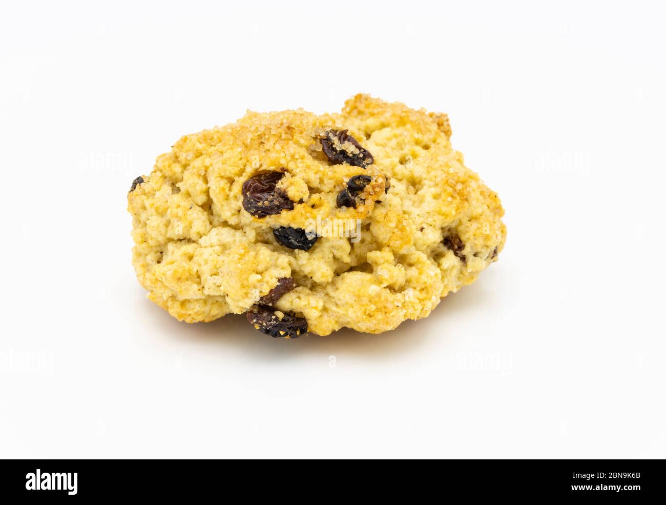 A single traditional delicious fresh golden home baked rock cake with raisins and brown sugar crystals viewed close up against a white background Stock Photo