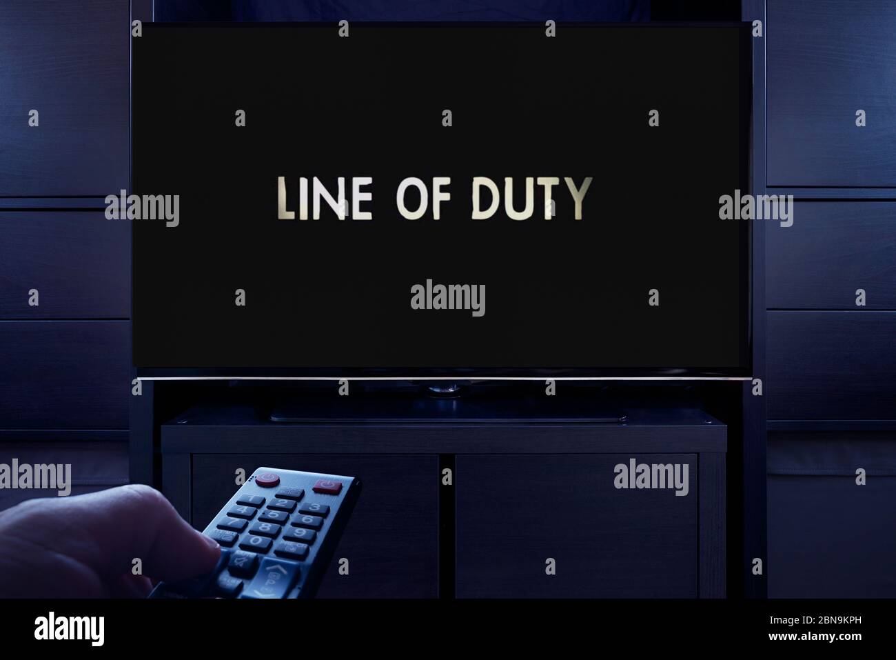 A man points a TV remote at the television which displays the Line of Duty main title screen (Editorial use only). Stock Photo