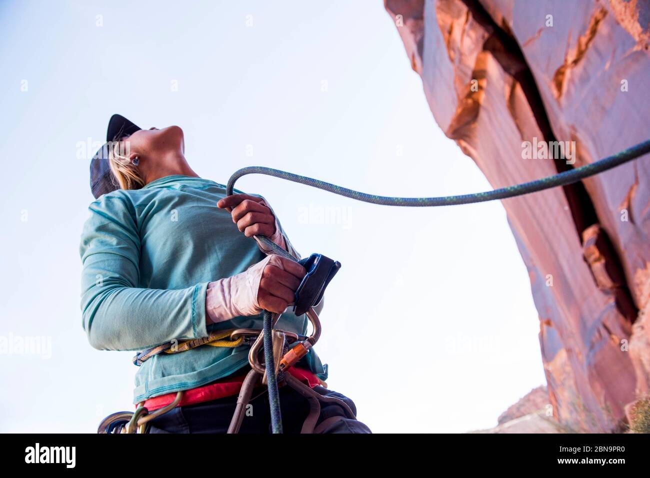 A woman belaying her climbing partner in the desert Stock Photo Alamy