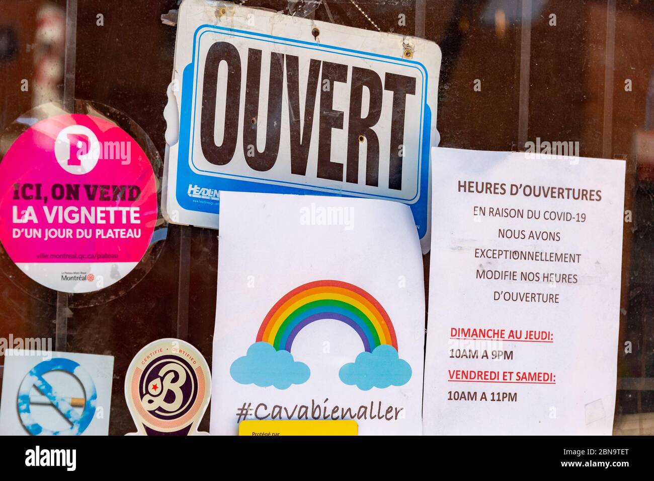 Montreal, CA - 13 May 2020: Ca va bien aller (Its going to be ok) message and Ouvert / Open sign on the door of a store during the Covid 19 pandemy Stock Photo