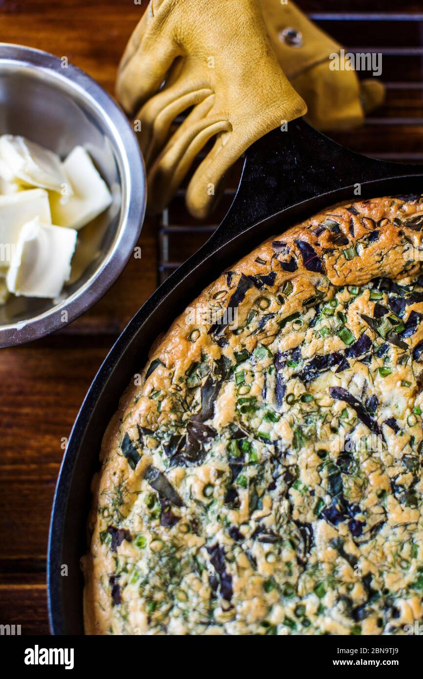 Castiron skillet with frittata and butter on wooden counter Stock