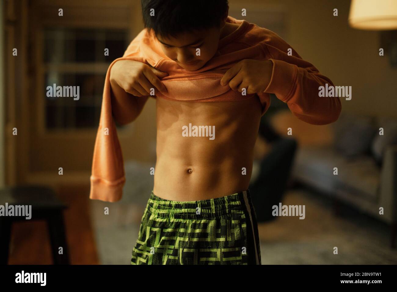 A 12-year old boy flexes his abdomen muscles Stock Photo